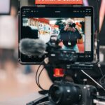 Videokamera mit aufgestecktem Tablet-Monitor an einem Stand der Photo+Adventure 2025