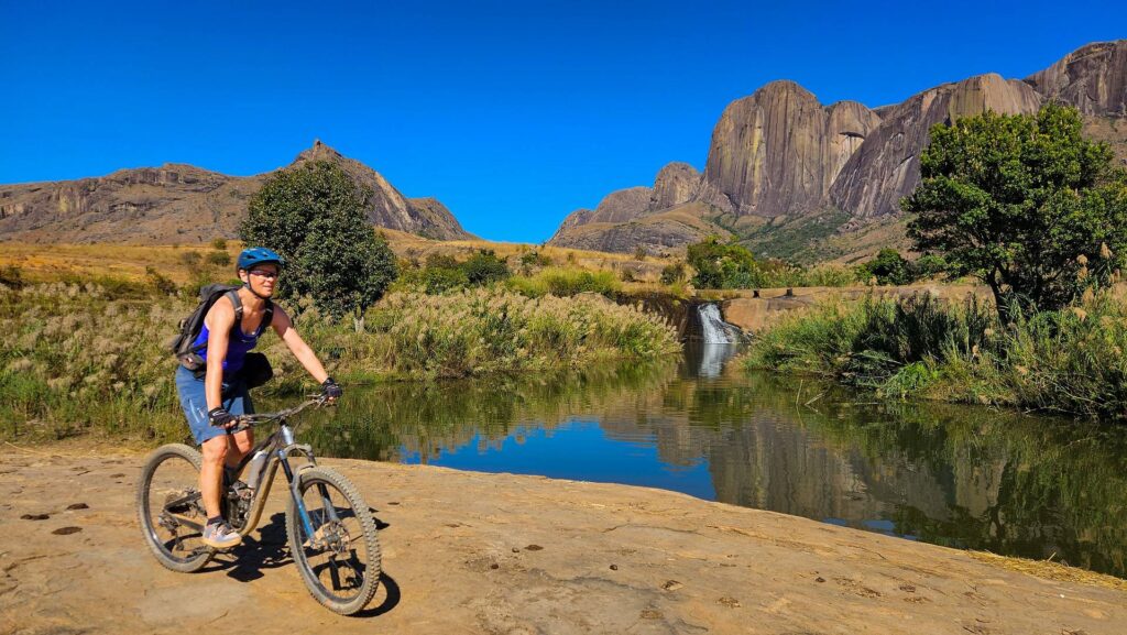 Mountainbikerin an einem Fluss vor Granitbergen in Madagaskar